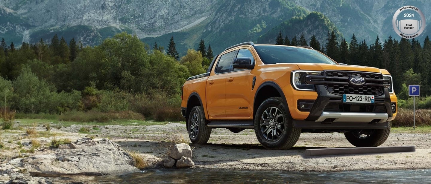 Orange Ford Ranger 3/4 front view on gravel in front of White Ford Ranger 3/4 rear view