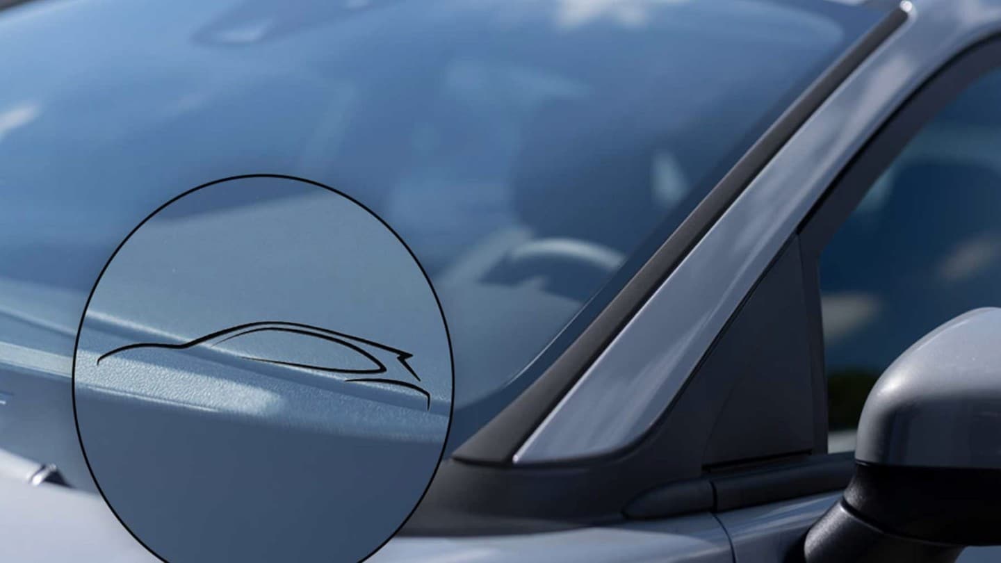  Zoom sur un pare-brise de voiture Ford avec le symbole d’un pare-brise certifié d’origine, visible à travers une loupe graphique.