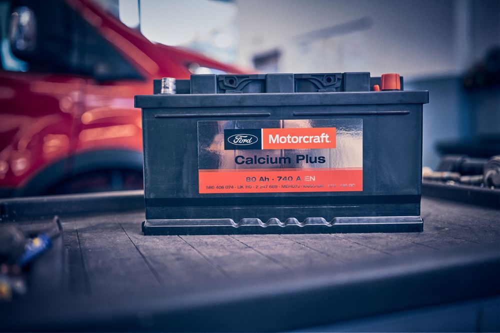 Batterie de voiture Ford avec un technicien en arrière-plan travaillant sur un véhicule