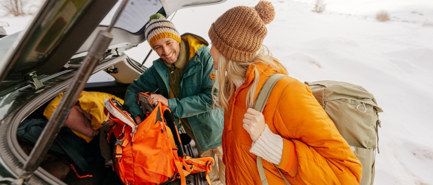 Un homme et une femme préparent leur sac à dos à l'arrière de leur véhicule