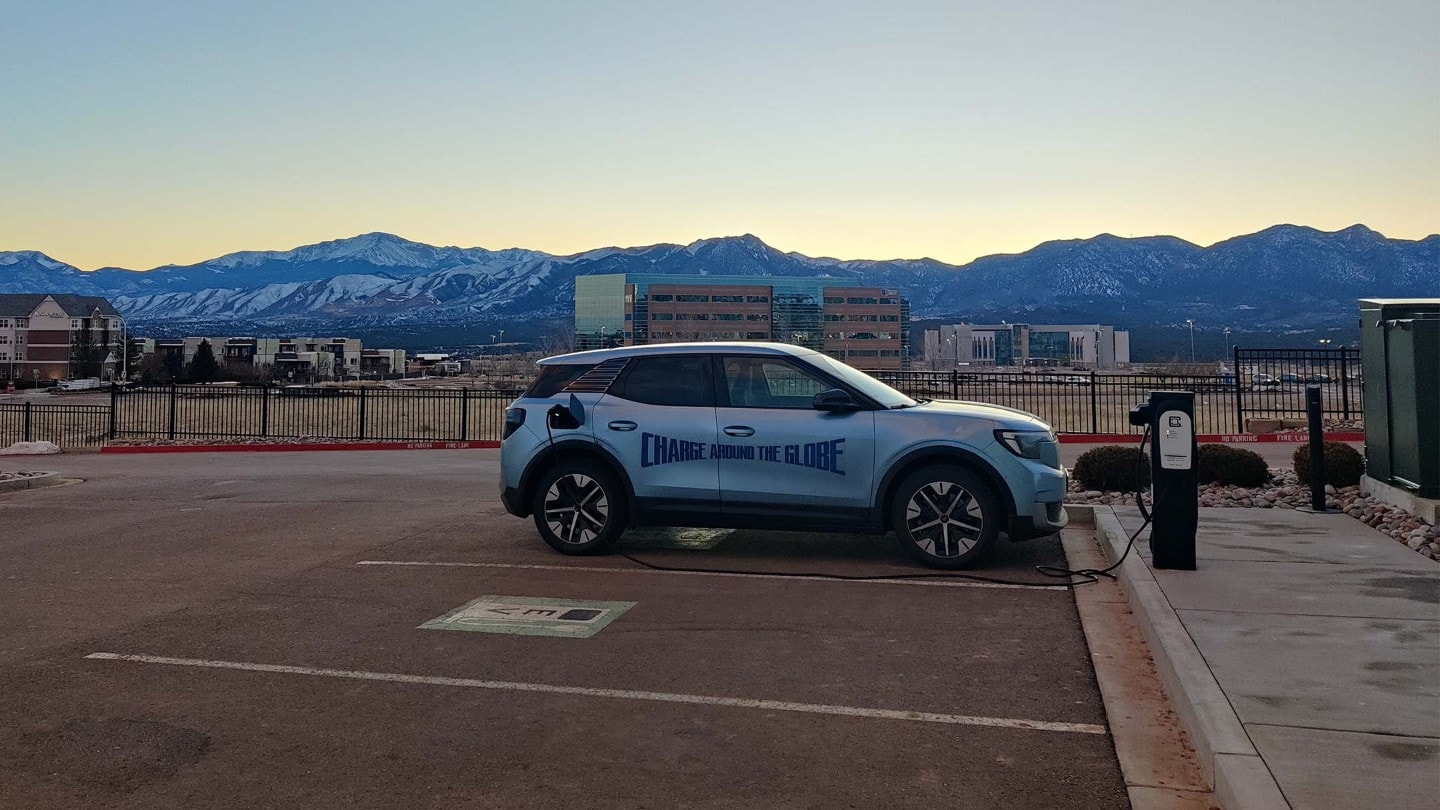 The electric Ford Explorer being charged with a mountaing in the background