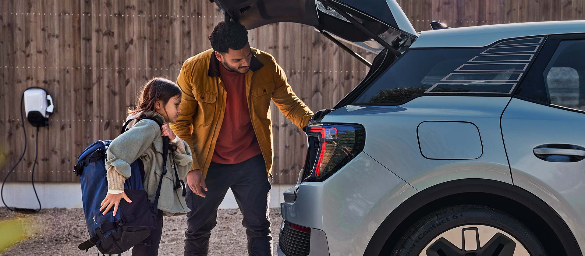 Une famille charge le coffre d'un Ford Explorer électrique bleu.