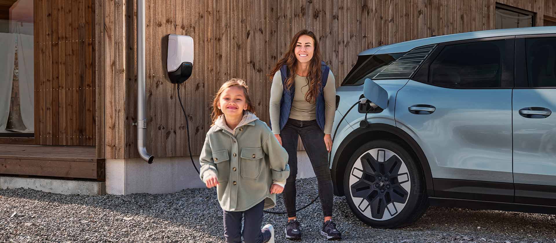 Une famille s'amusant à recharger son Ford Explorer électrique à l'aide d'un chargeur domestique extérieur pour VE.