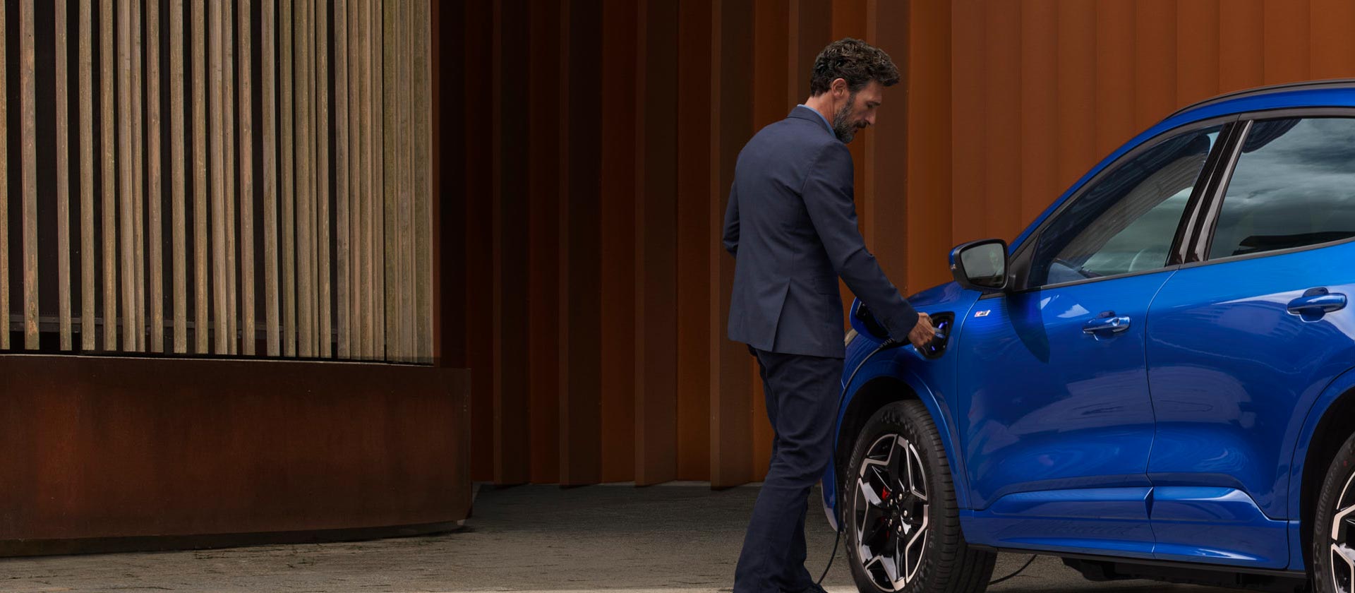 Une personne connectant une voiture hybride rechargeable Ford à un câble de recharge domestique VE.