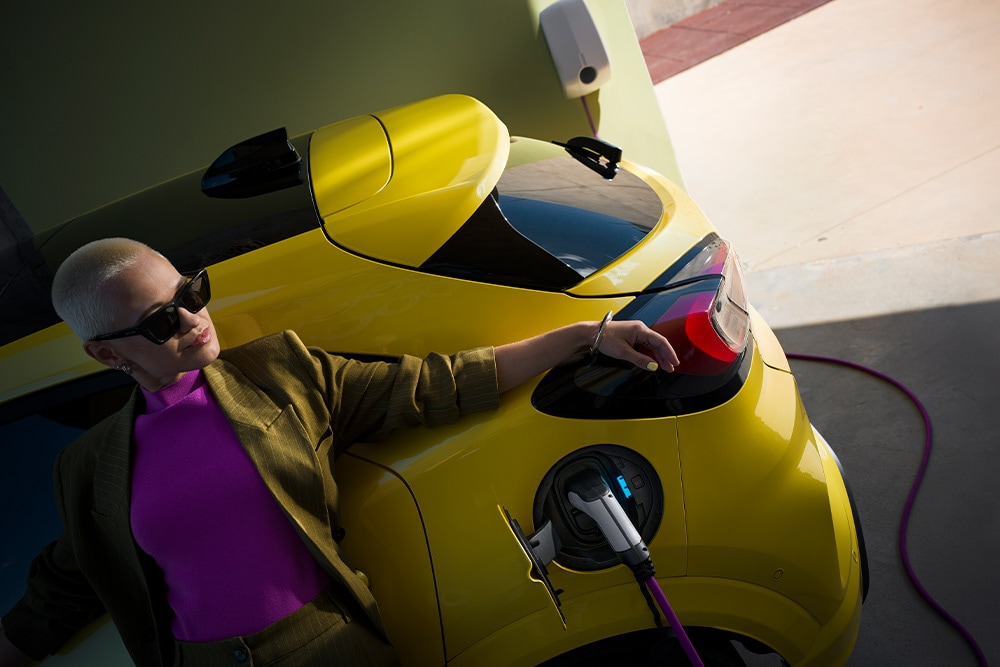 Une personne rechargeant une Ford Capri électrique jaune. 
