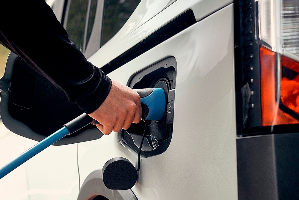 Une personne connectant un véhicule électrique Ford à un câble de recharge pour VE.