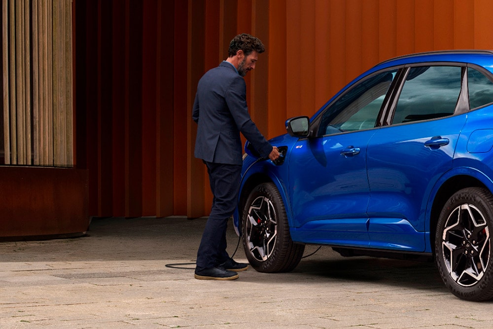 Une personne qui branche un câble de recharge domestique VE sur une voiture hybride rechargeable Ford.