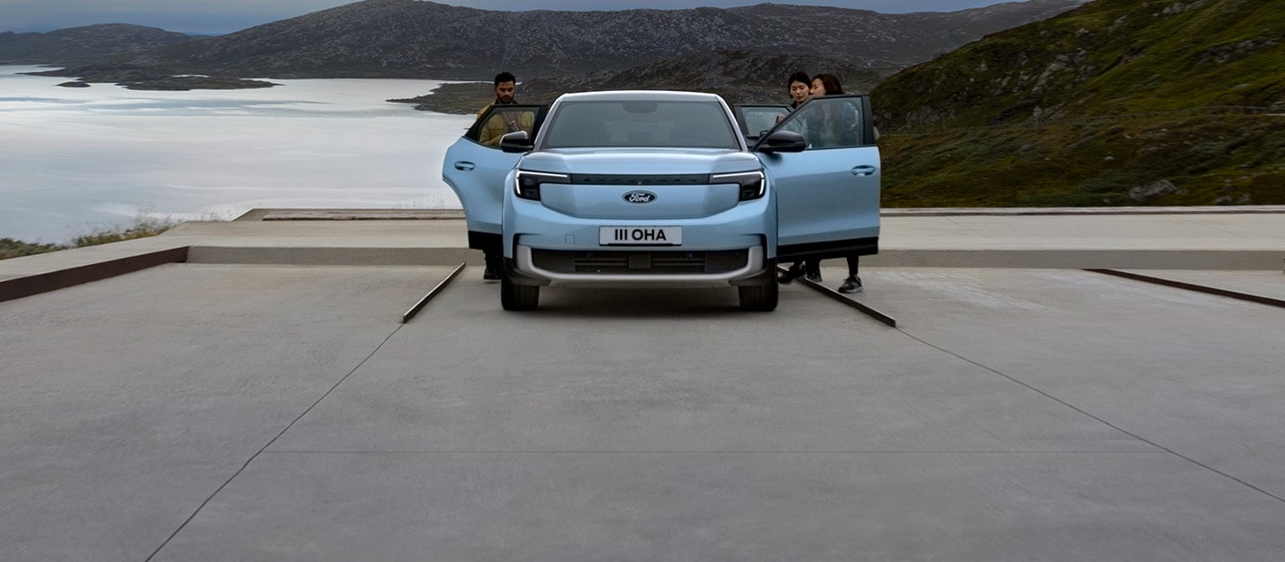 Un Ford Explorer électrique bleu garé au bord d'un lac avec les portières ouvertes et trois personnes autour.