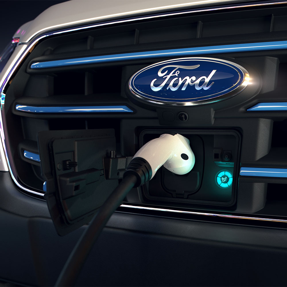 Gros plan d'une borne de recharge pour fourgonnette Ford E-Transit et d'un badge bleu ovale Ford sur la calandre. 