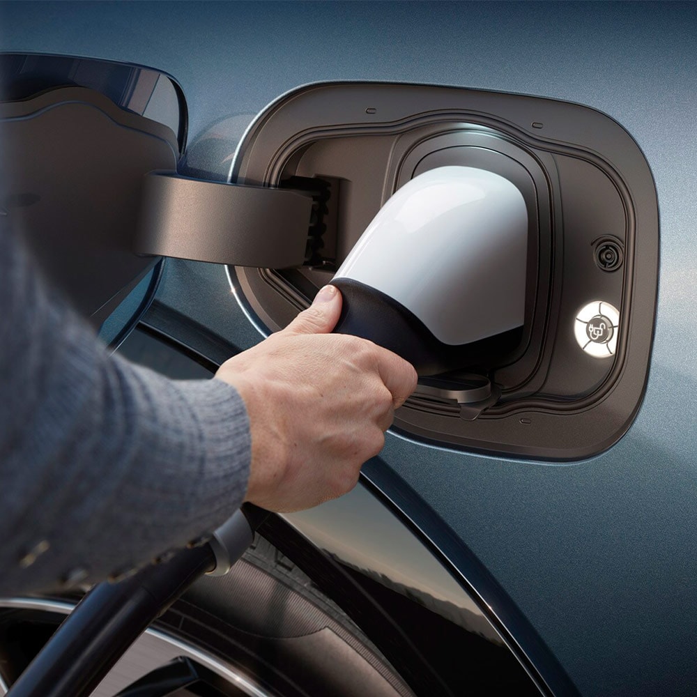 Une personne branche un chargeur  ultra-rapide sur un véhicule électrique Ford. 