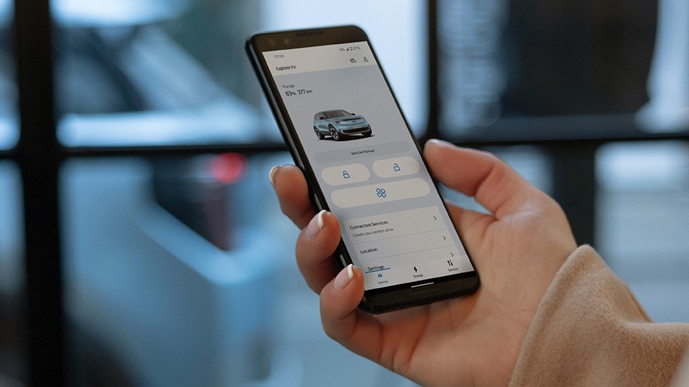 Gros plan d’une main tenant un smartphone et interagissant avec l’application FordPass.