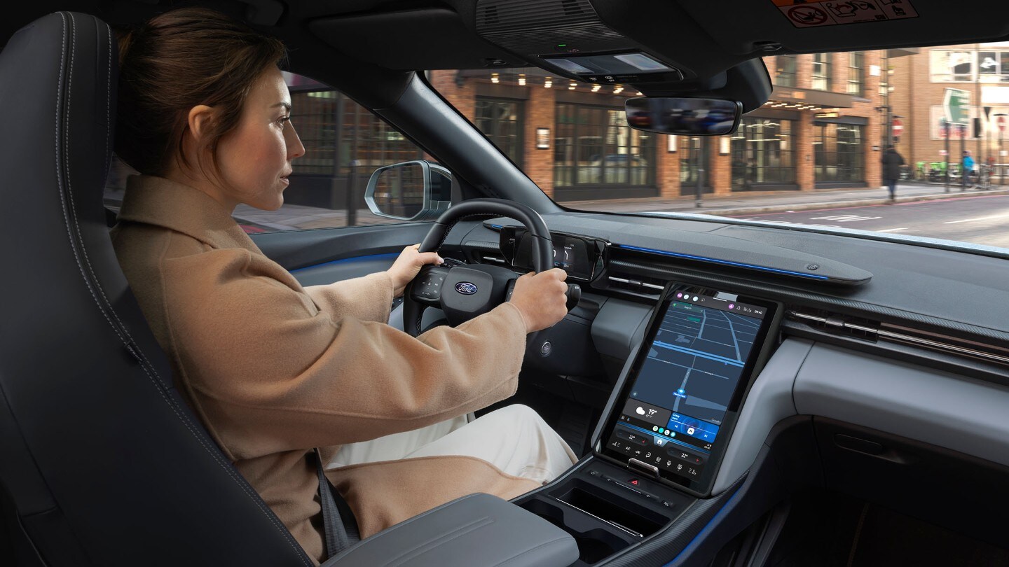 Photo intérieure d’une femme conduisant le Ford Explorer sur une route urbaine. 