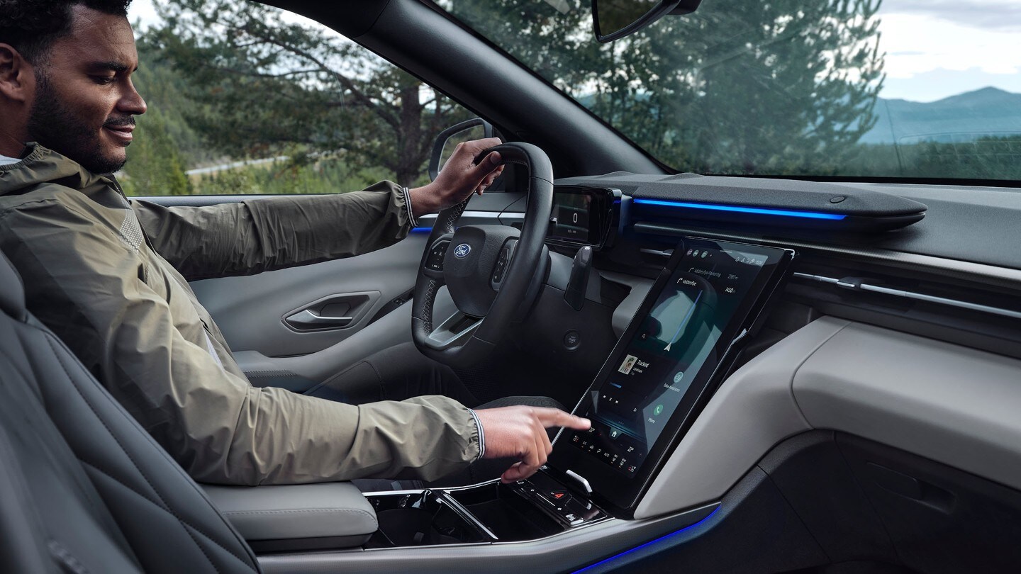 Un homme assis au volant du Ford Explorer, interagissant avec le grand écran tactile SYNC.