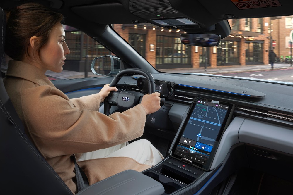 Photo intérieure d’une femme conduisant le Ford Explorer sur une route urbaine. 