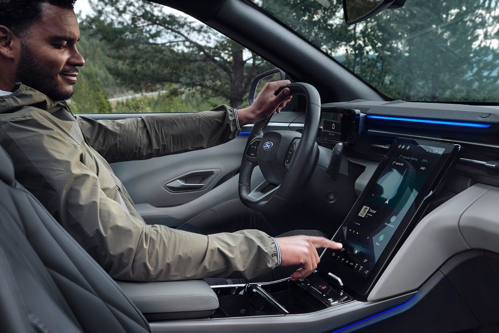 Un homme assis au volant du Ford Explorer, interagissant avec le grand écran tactile SYNC.