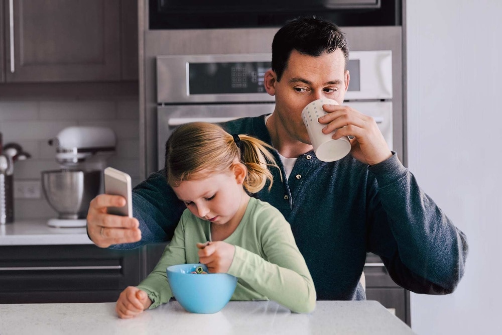 Homme avec un enfant consultant son téléphone portable