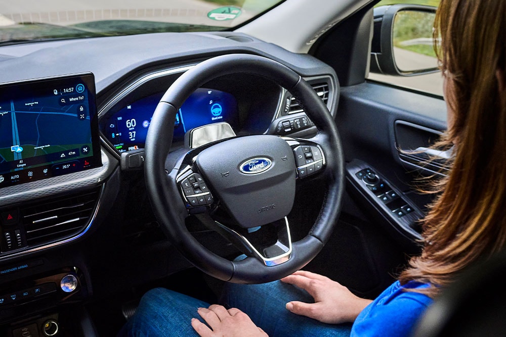 Une femme lâche le volant de son Kuga équipé de la technologie BlueCruise .