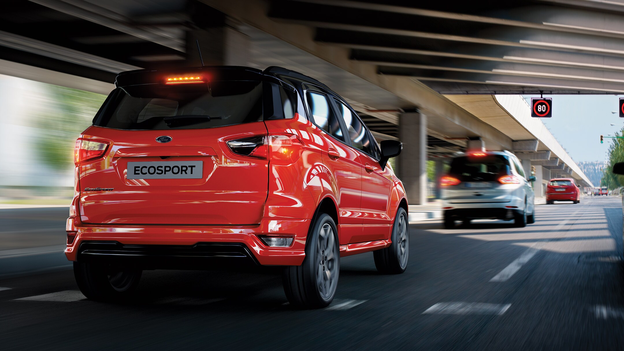 Red Ford EcoSport from the back heading towards traffic sign
