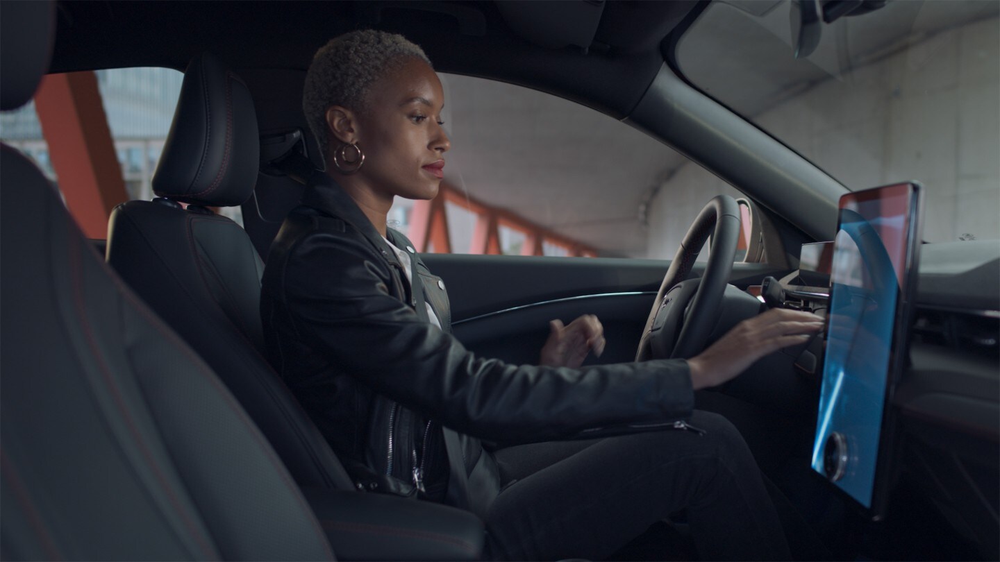 Une femme assise dans la Ford Mustang Mach-E utilisant l'écran tactile SYNC 4.