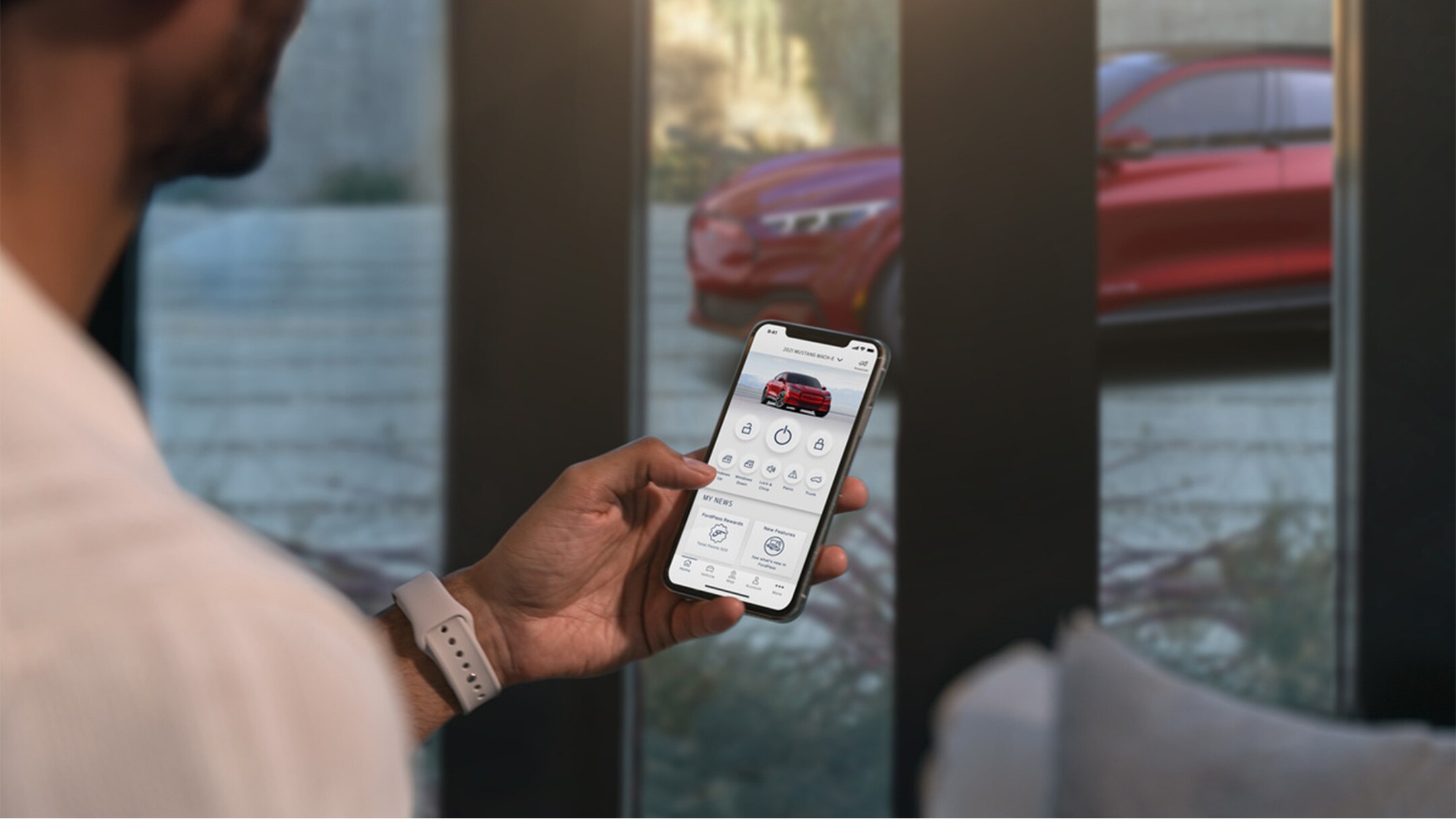 Un homme tenant un smartphone ouvert sur l’application FordPass