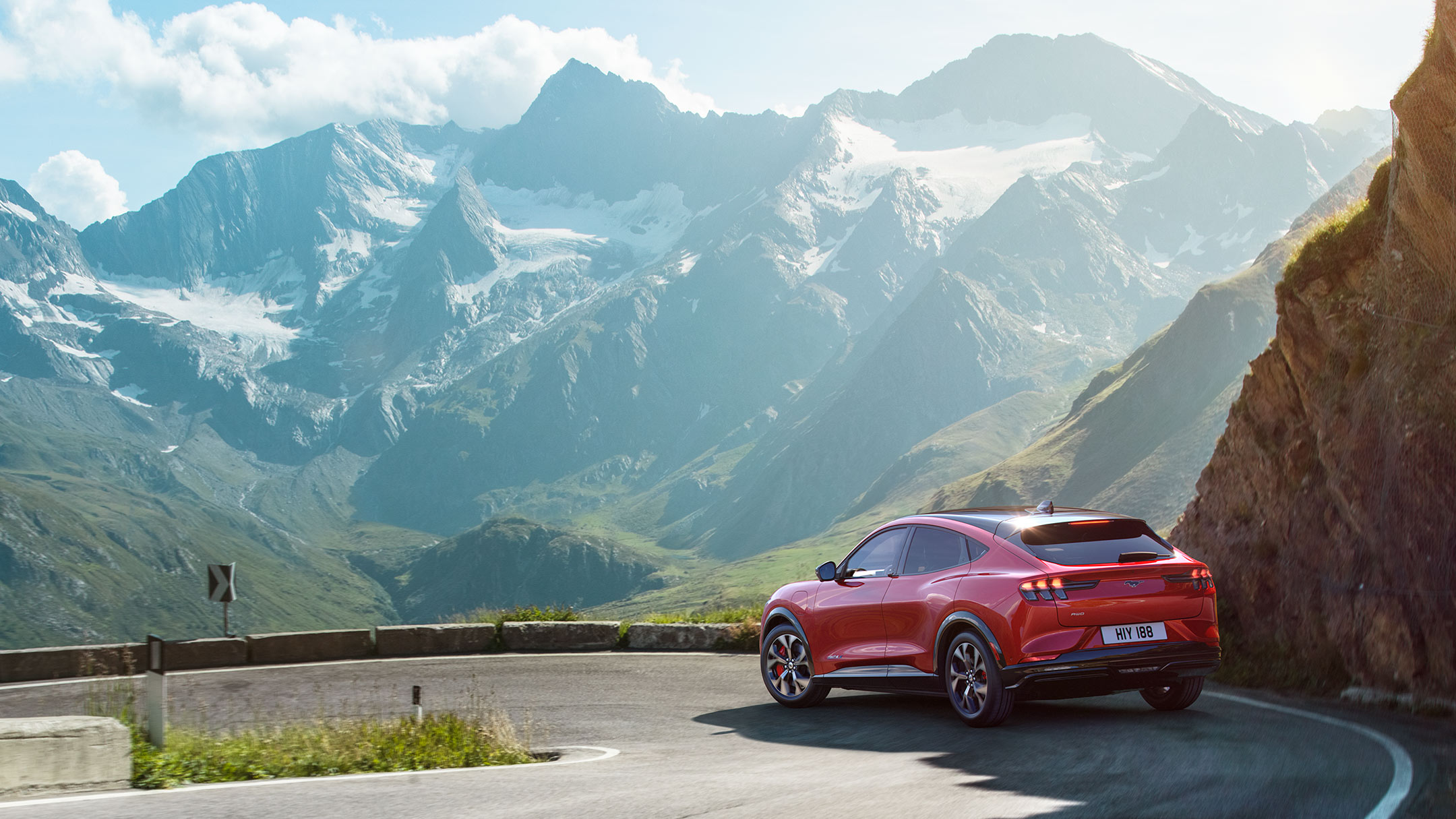 La Nouvelle Ford Mustang Mach-E rouge roulant à travers les montagnes.