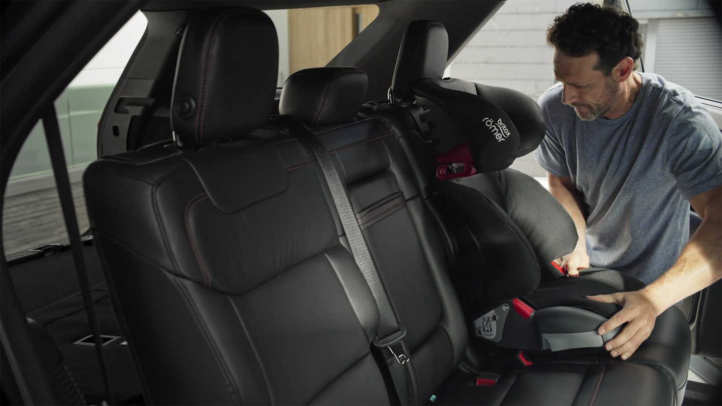 Un homme installant un siege enfant à l’arrière du Ford Explorer. 