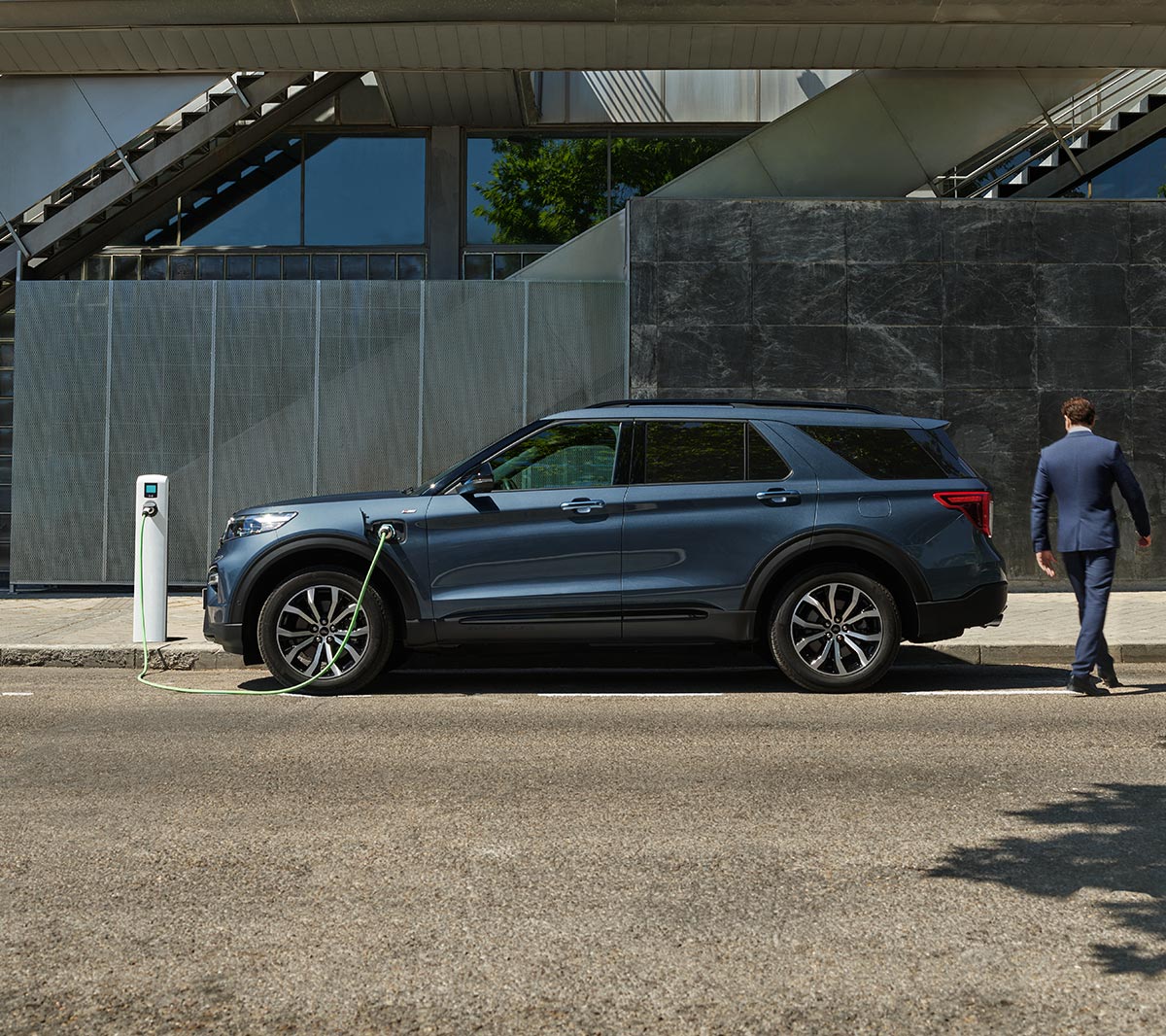 Un homme a coté du Ford Explorer et d’une borne de recharge.