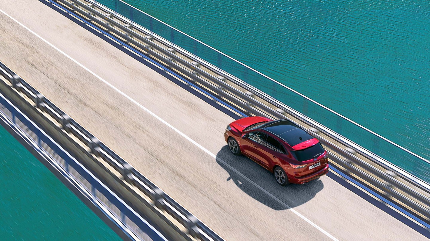 Le Ford Kuga rouge roulant sur un pont au-dessus de l’eau