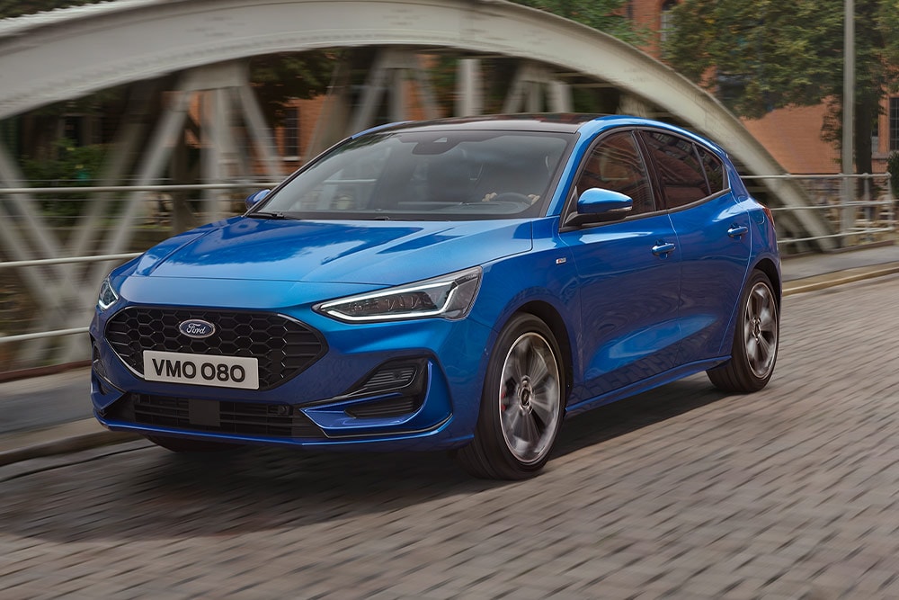 Une Ford Focus bleue à hayon roulant sur un pont.