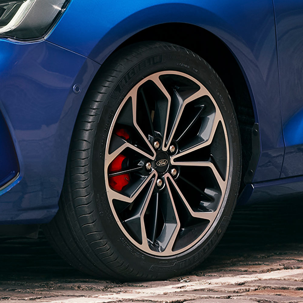 Gros plan sur les jantes en alliage gris avec étriers de frein rouges d'une Ford Focus bleue.