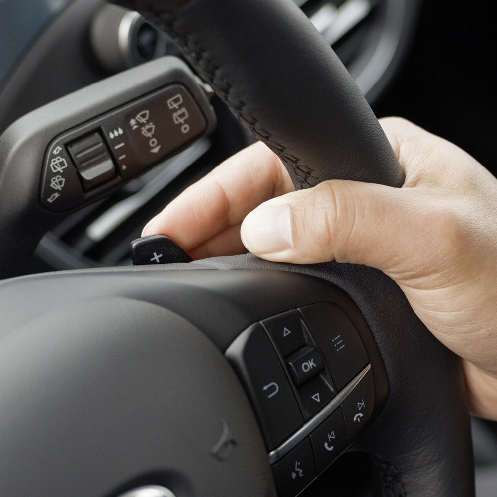 Gros plan d'une main actionnant les palettes de changement de vitesse de la Ford Focus situées derrière le volant.