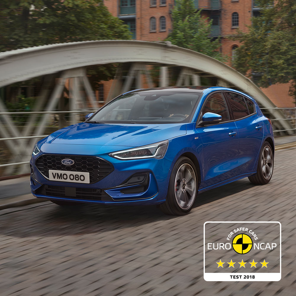 Une Ford Focus bleue garée sur un pont, avec l'insigne de sécurité Euro NCAP cinq étoiles dans le coin inférieur droit.