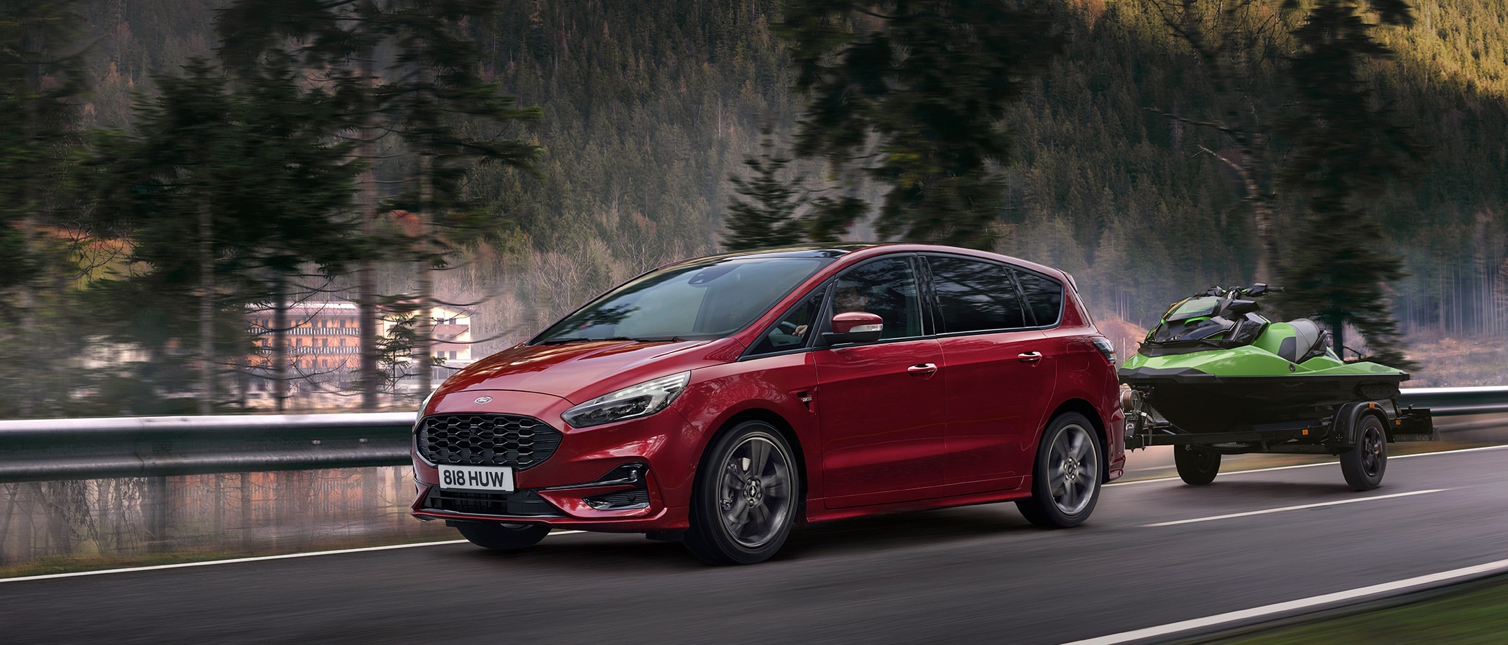 Ford S-MAX Hybrid driving past a forest background.