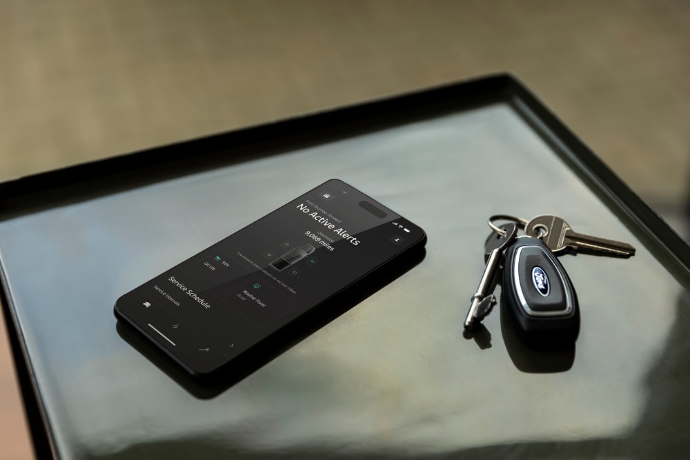 A smartphone displays the Ford App with vehicle status, next to a Ford car key.