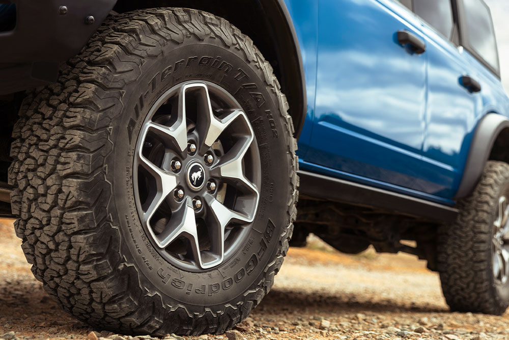 A close up view on the all-terrain tyres of a blue Ford Bronco.