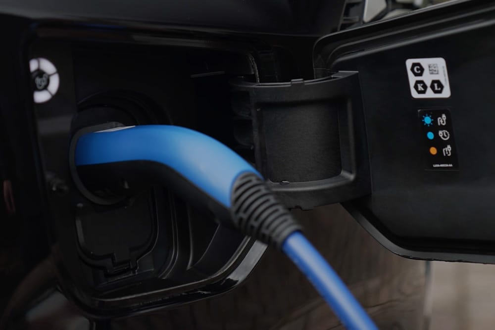 Gros plan d’un câble de recharge bleu branché sur un port de charge de véhicule électrique.