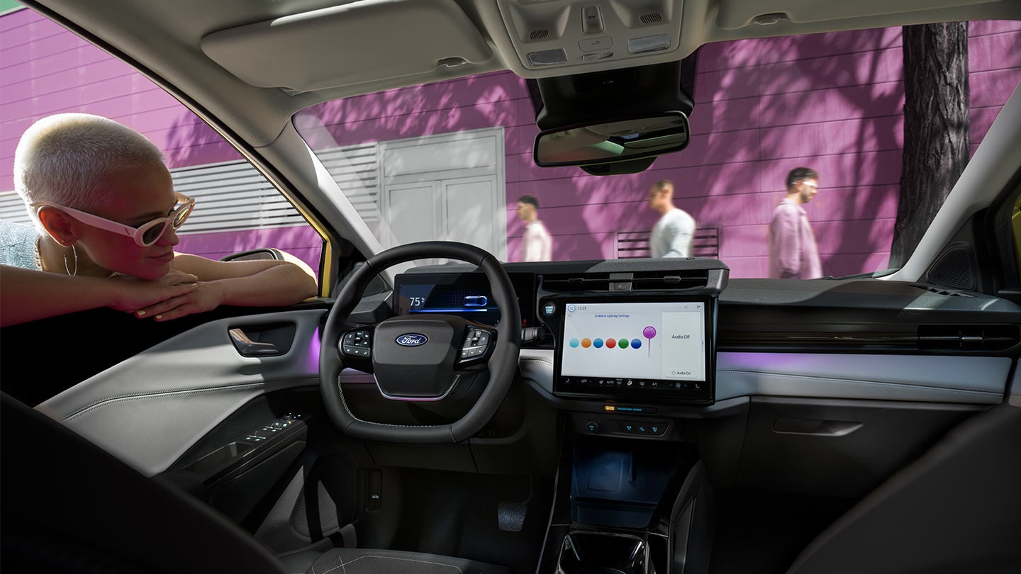 Personne regardant à l’intérieur de la nouvelle Ford Puma Gen-E®, montrant le grand écran tactile et l’éclairage ambiant.