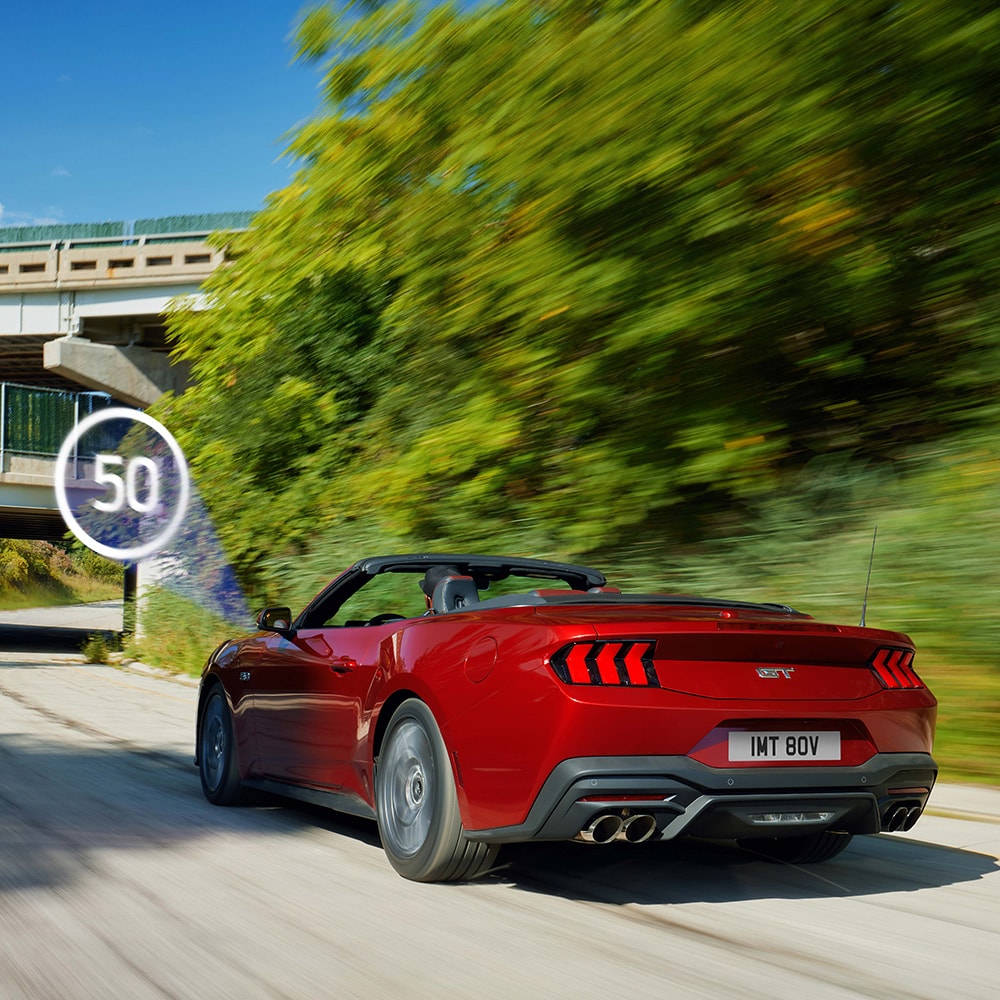 Ford Mustang rouge sur une route avec panneau de signalisation