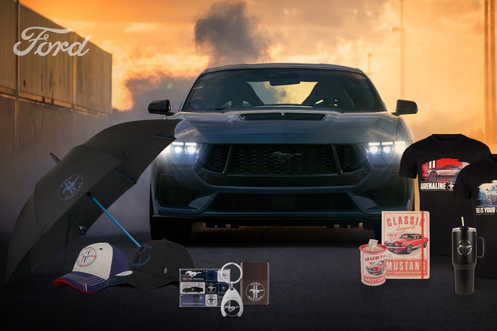 Collection Ford Mustang : Mustang grise en arrière‑plan et merchandising parapluie, casquettes, mugs, t‑shirts.