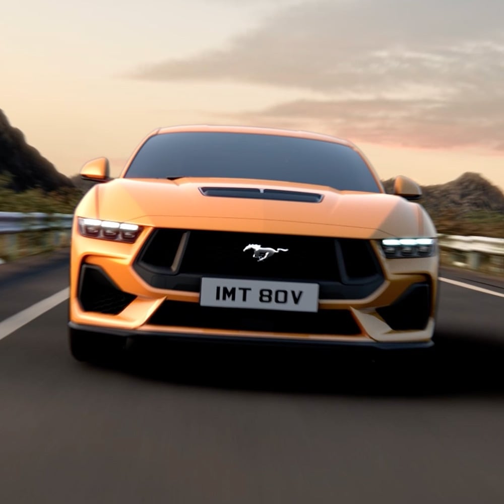 Vue avant d’une Ford Mustang orange avec gros plan sur les phares, la calandre et l’emblème Mustang