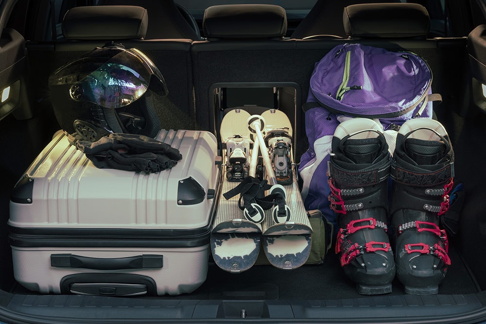 Le compartiment à bagages arrière du Ford Explorer rempli d’une valide blanche et d’équipements de ski placé par le hayon à bagage.