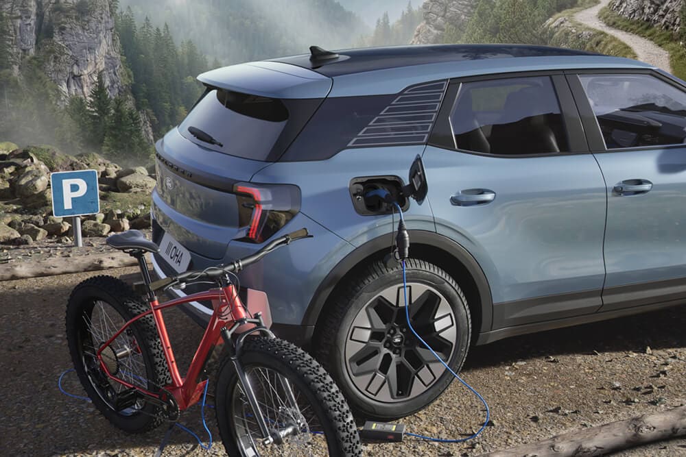 Un vélo électrique en charge depuis un Ford Explorer®, avec un paysage montagneux en arrière-plan.