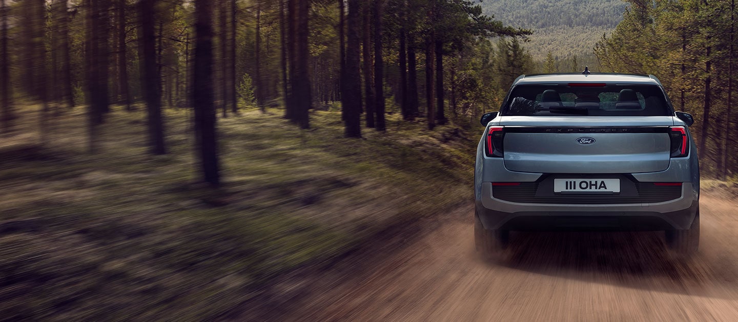 A rear view of Ford Explorer® driving through a forest