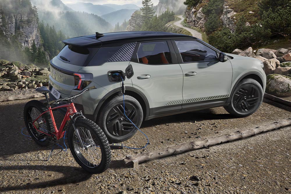 Un vélo électrique en charge depuis un Ford Explorer®, avec un paysage montagneux en arrière-plan.