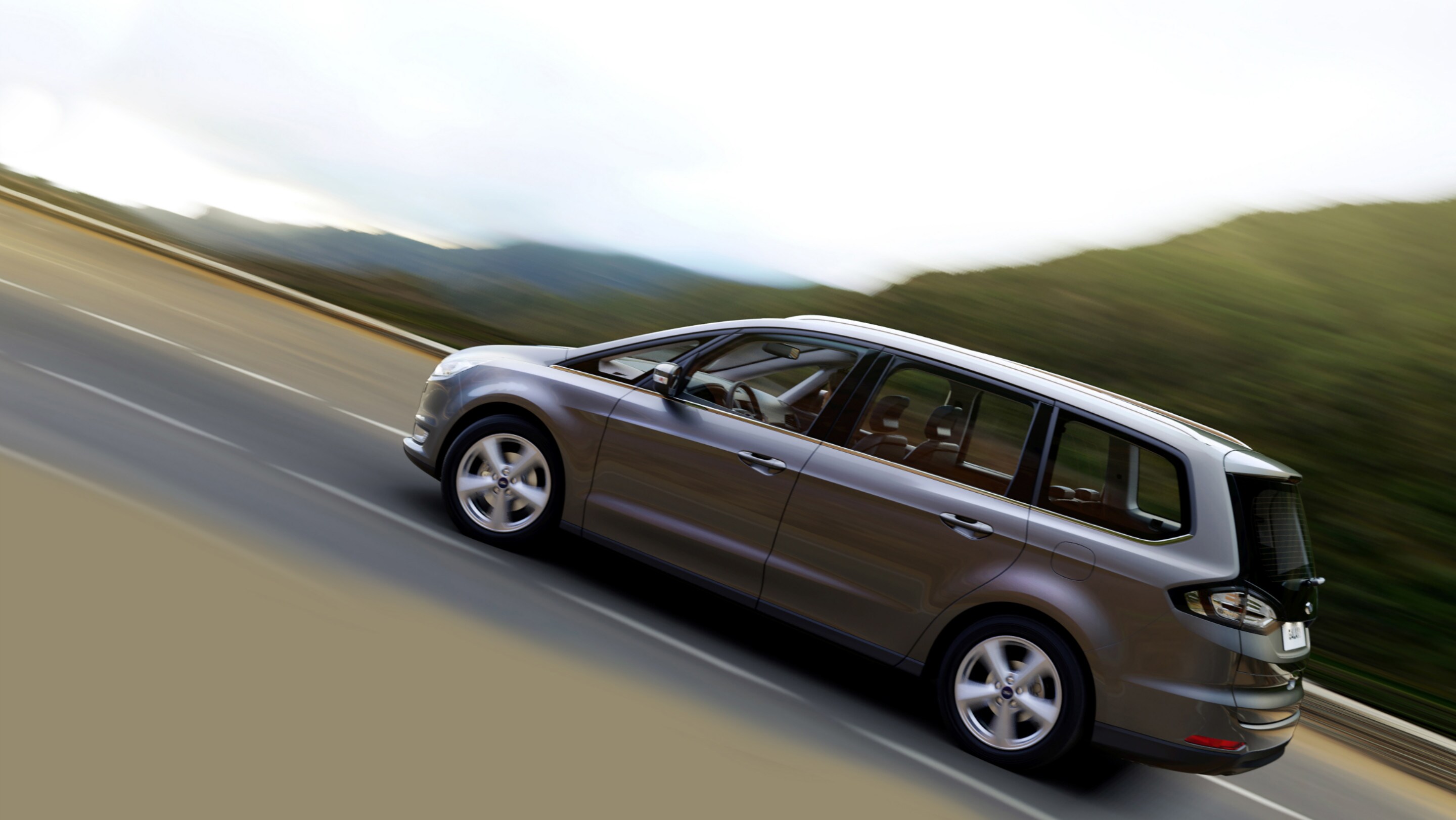Grey Ford Galaxy driving uphill on the road