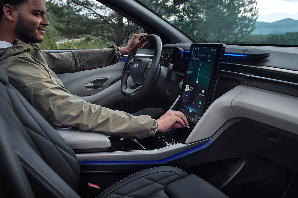 Un conducteur utilise le système d’infodivertissement à écran tactile à bord du SUV familial Ford Explorer.