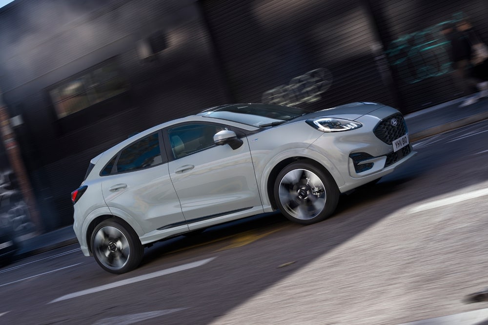 Ford Puma argenté de la gamme de citadines Ford, circule dans une rue.