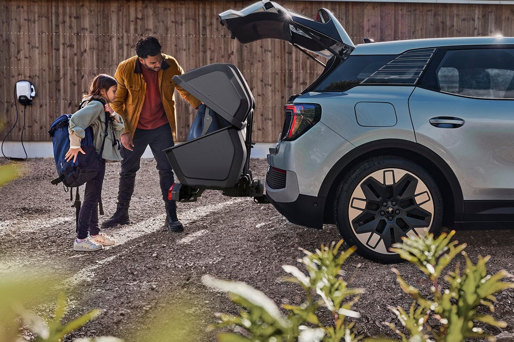 Un homme et un enfant se tiennent près du coffre ouvert d’un SUV Ford Explorer et chargent une poussette pliée.
