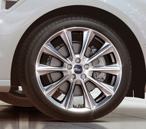 White Ford S-MAX Vignale headlight close-up with wheel and part of a grille