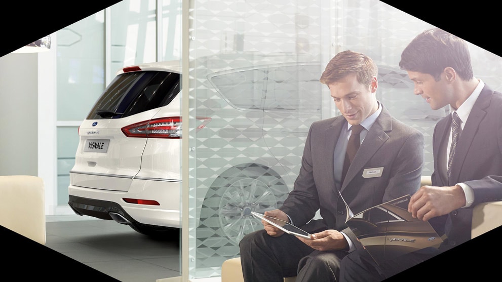 Two men looking thgrough Vignale brochures with white Ford S-MAX Vignale in the background